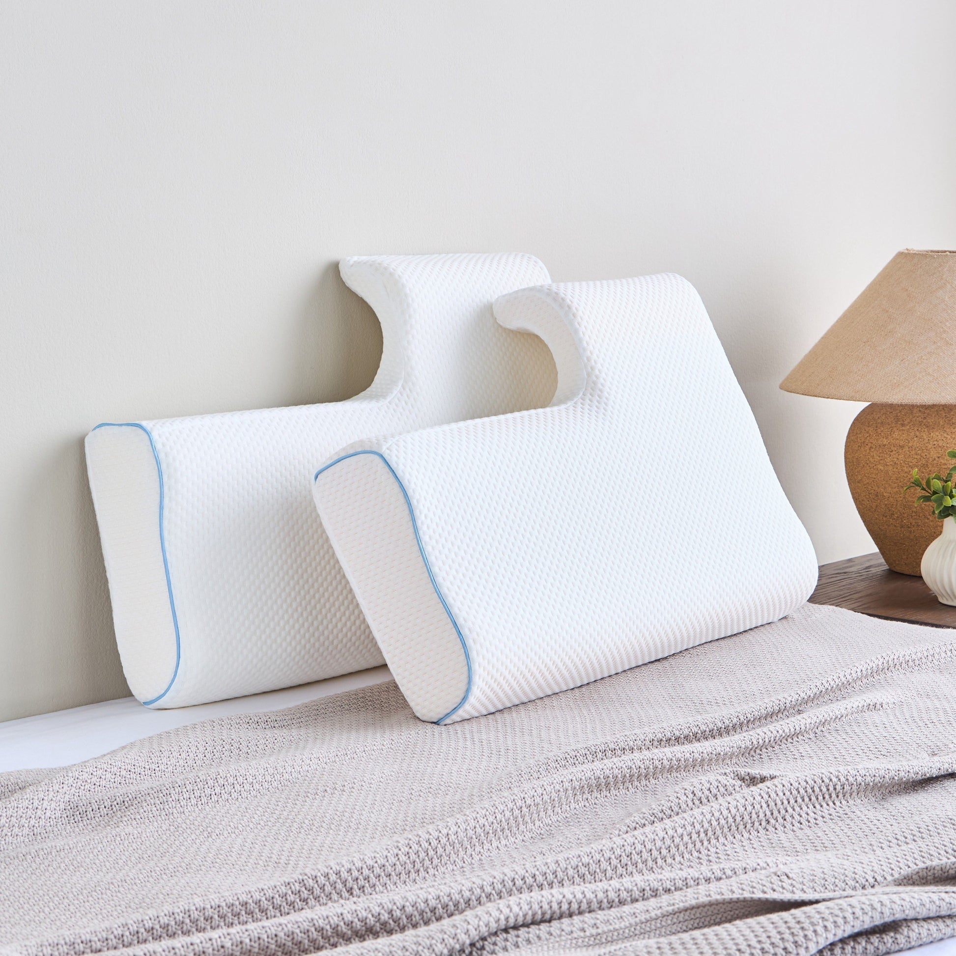 Two white pillows with blue accents on a bed in a bedroom setting.