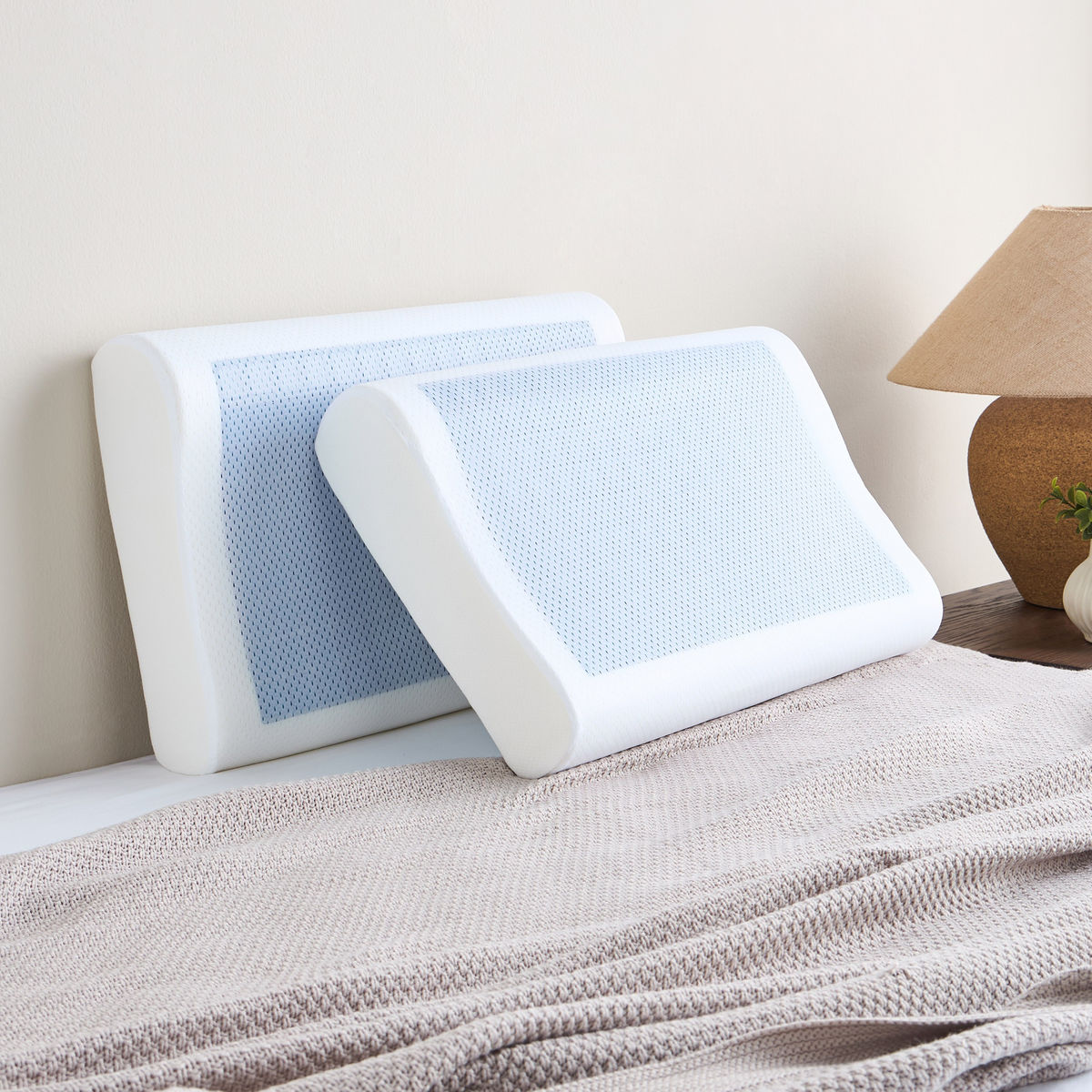Two white pillows with blue mesh on a bed in a bedroom setting.