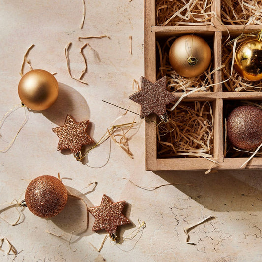 Decorative Christmas ornaments including gold and bronze balls and stars on a textured surface.