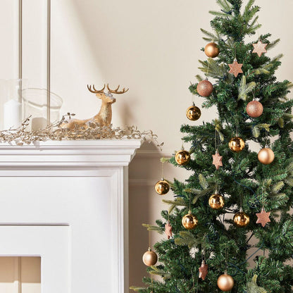 Decorated Christmas tree with gold and bronze ornaments next to a fireplace with a gold deer ornament.