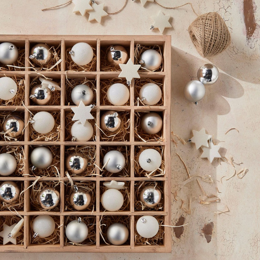 Wooden box with Christmas ornaments including balls and stars on a textured surface.