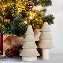 Wooden Christmas tree decorations in front of a decorated tree.