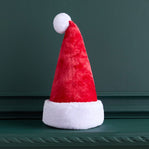 Red Santa hat with white trim on a dark green surface