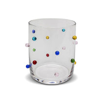 Clear glass tumbler with multicolored dots on a white background