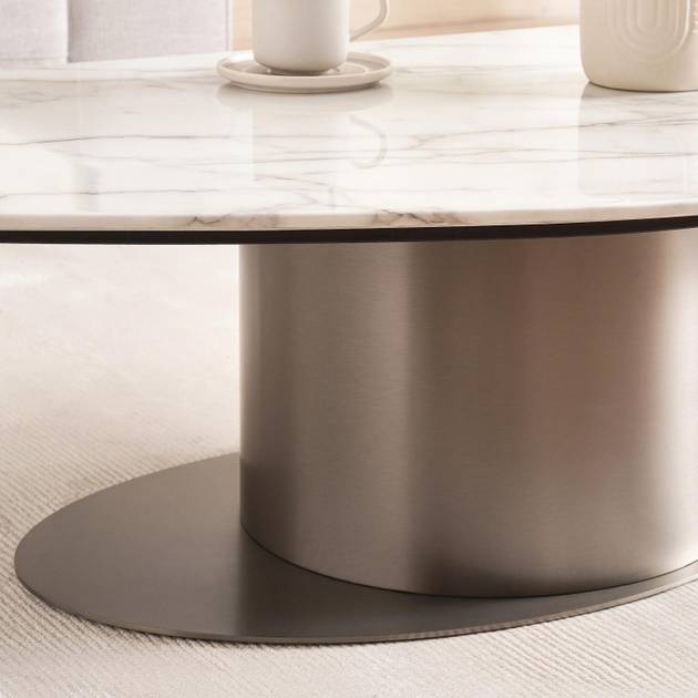 Round marble coffee table with a metallic base on a light wood floor.