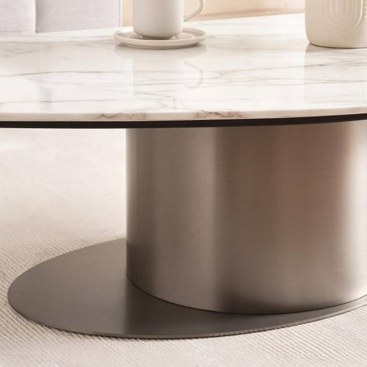 Round marble coffee table with a metallic base on a light wood floor.