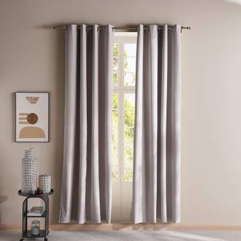 Gray curtains hanging in a room with a small table and decor items.