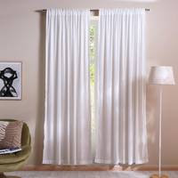 White curtains in a room with a chair, lamp, and abstract art on the wall.