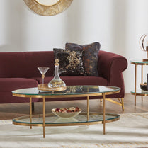 Living room with a burgundy sofa, glass coffee table, and decorative items.