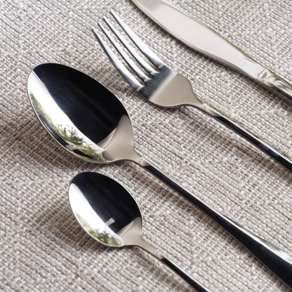 Set of silver cutlery including spoons and a fork on a textured surface- Evren 24-Piece Cutlery Set – Chrome Finish