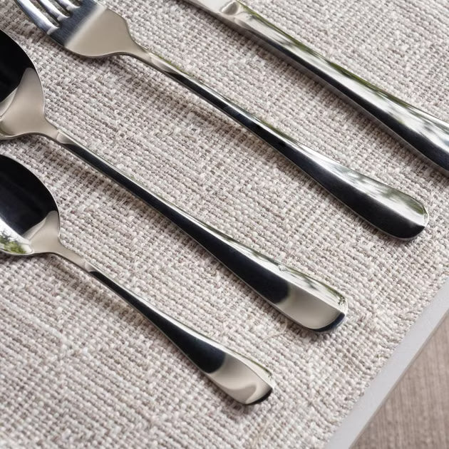 Set of silver cutlery including forks and spoons on a textured surface- Evren 24-Piece Cutlery Set – Chrome Finish