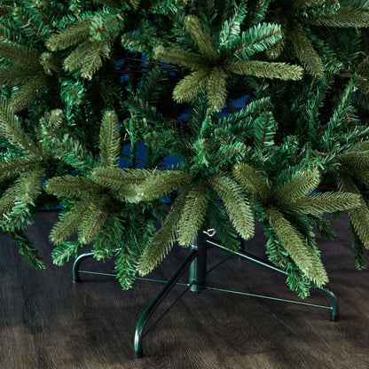 Green artificial Christmas tree on a stand against a dark background