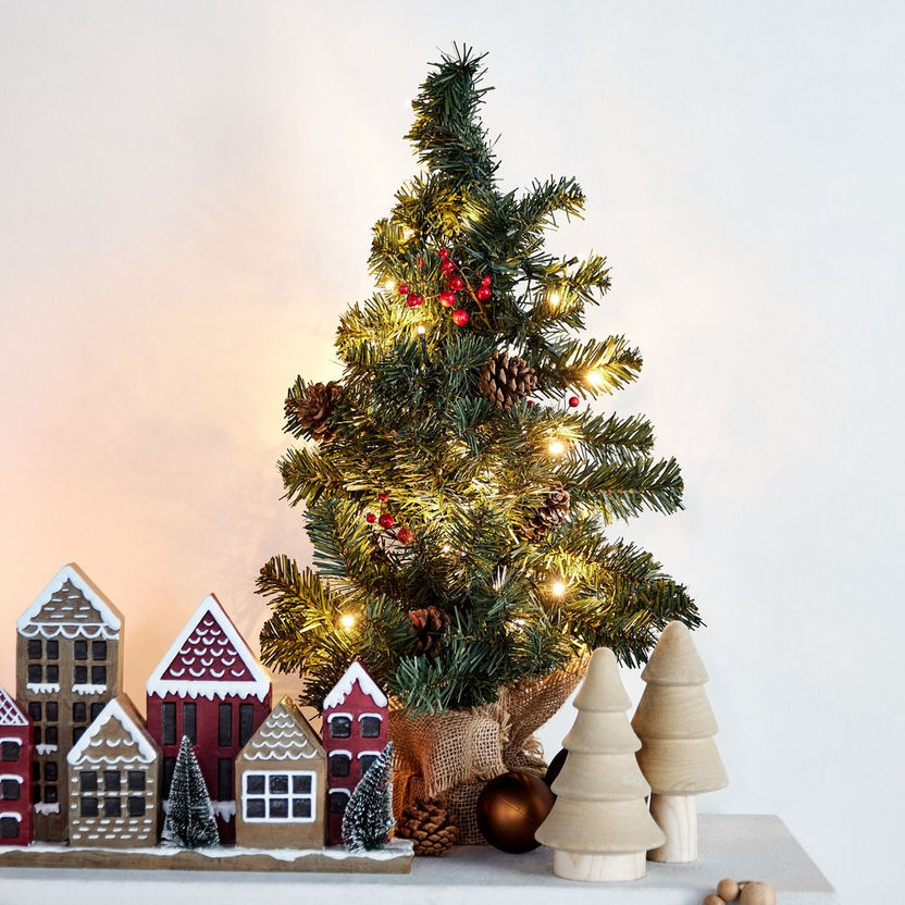 Decorative Christmas scene with a small tree, gingerbread houses, and wooden trees on a white background.