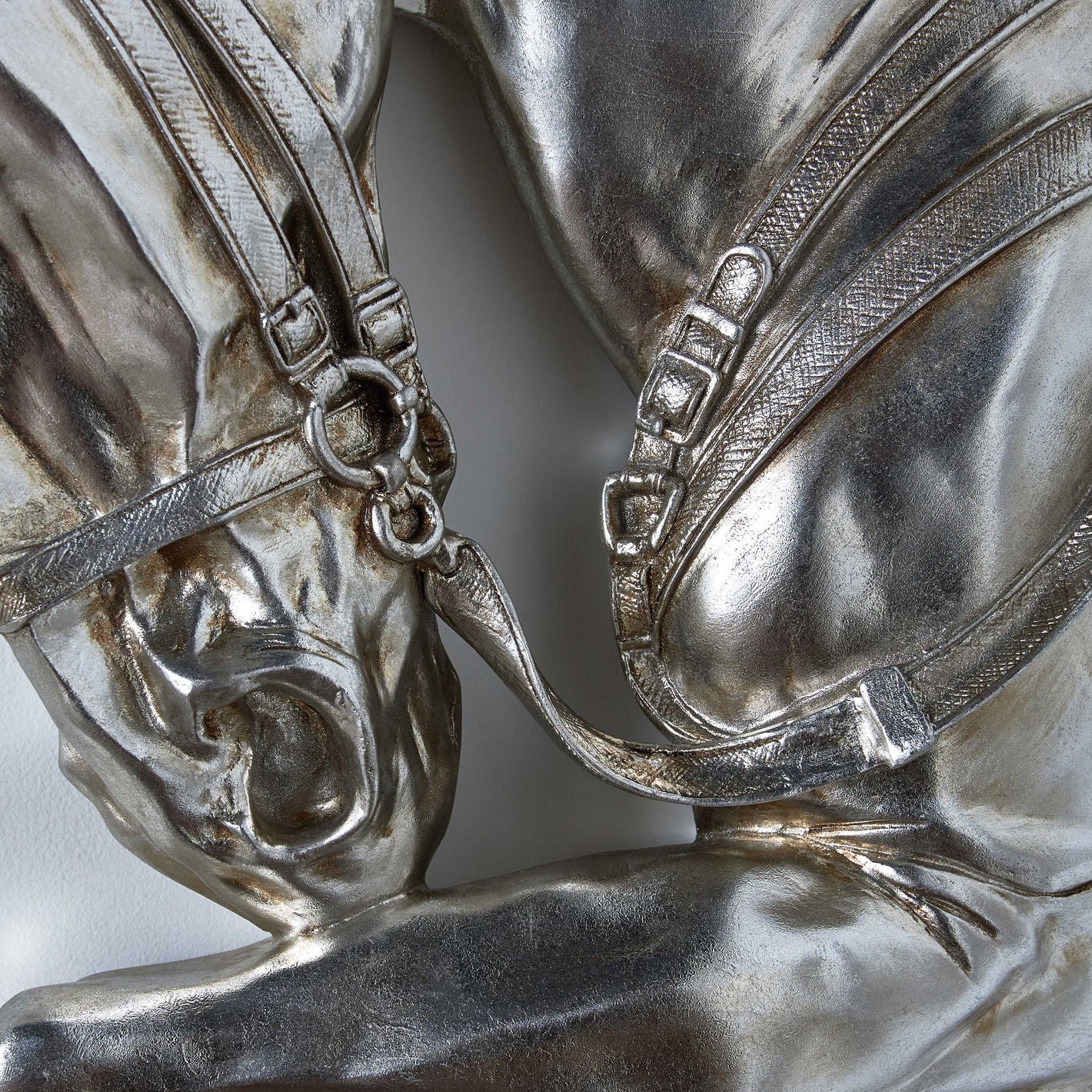 Close-up of a silver horse figurine with detailed bridle and reins.
