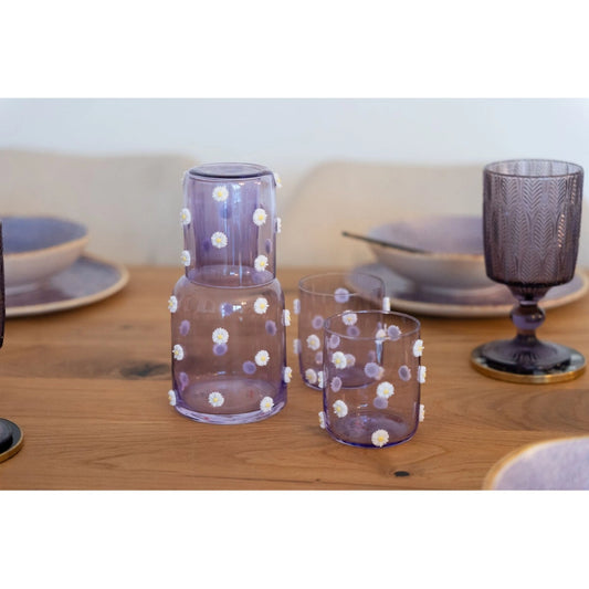 Set of purple glassware with white polka dots on a wooden table.
