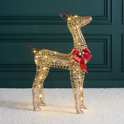 Decorative wire reindeer with lights and a red bow against a dark green wall.