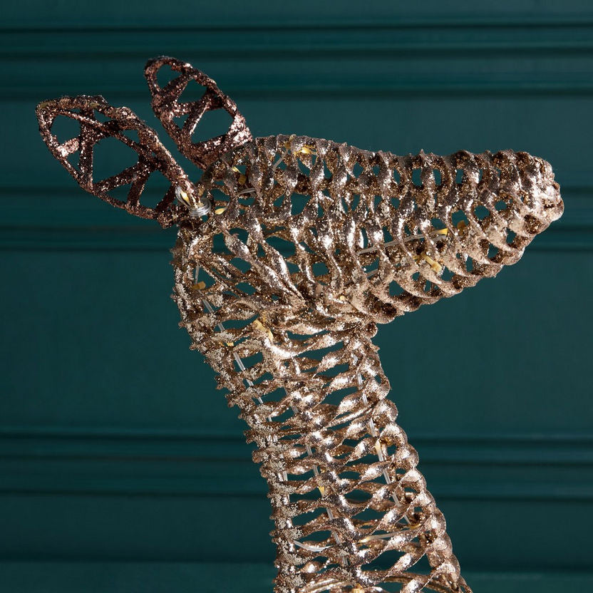 Decorative metallic deer figure against a dark green background