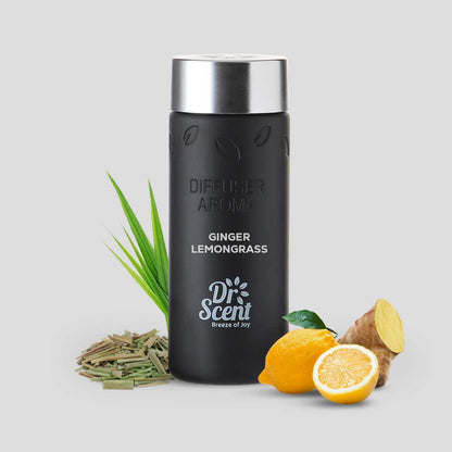 Black diffuser aroma bottle with silver cap, surrounded by ginger, lemongrass, lemon, and grass on a light gray background.