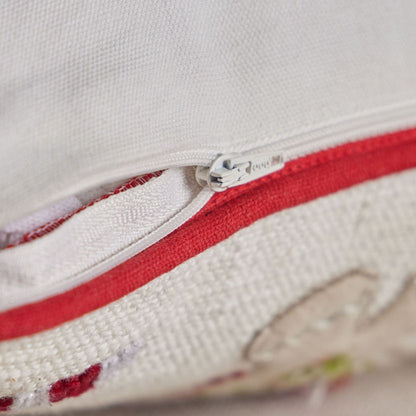 Close-up of a zipper on a white and red fabric with floral patterns.