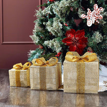Three gold-wrapped presents under a decorated Christmas tree.