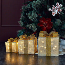 Decorative gold gift boxes with lights under a Christmas tree.