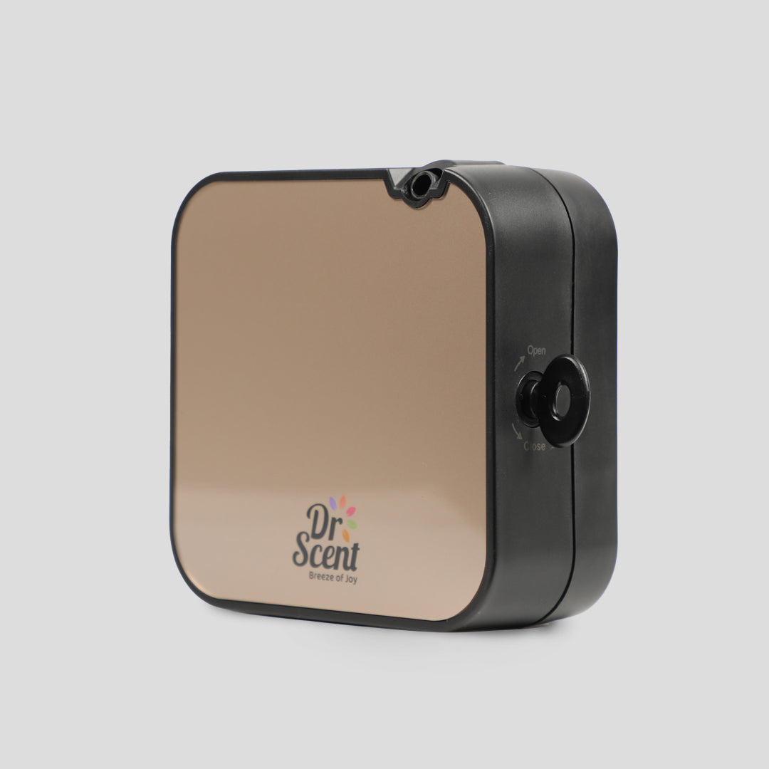 A square-shaped fragrance diffuser with a black front and a logo that reads 'DR SCENT' on the front. It has a black lid and a visible power button.