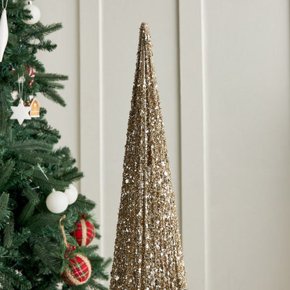 Decorative gold cone tree next to a Christmas tree with ornaments on a light wooden panel background