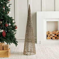 Decorative cone Christmas tree next to a decorated Christmas tree with presents and a fireplace.