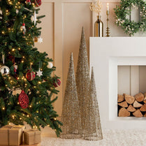 Decorative Christmas scene with a tree, gift boxes, and metallic trees in front of a fireplace.