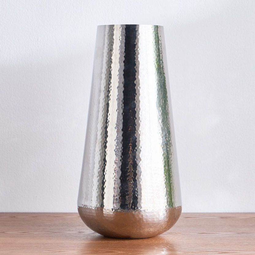 Silver textured vase on a wooden surface with a white background