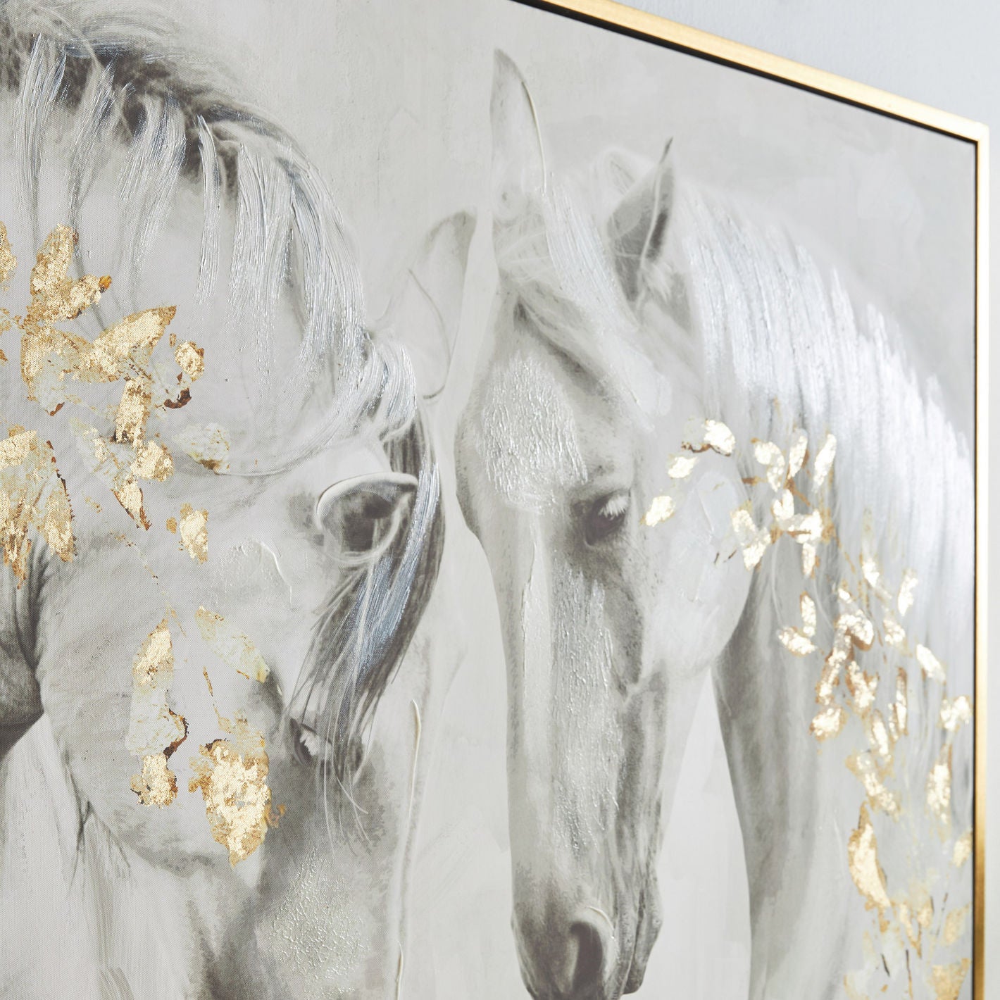 Framed artwork of two horses with gold leaf accents on a light gray background