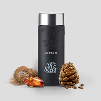 Black diffuser aroma bottle with silver cap, surrounded by decorative elements on a light gray background