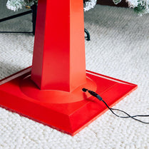 Red Christmas tree stand on a textured surface with a blurred background