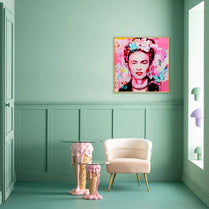 Frida Kahlo artwork on a mint green wall with a pink chair and ice cream-themed table.