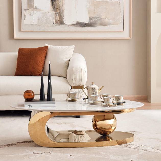 Modern living room with a gold coffee table, white sofa, and abstract art on the wall.