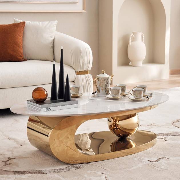Modern living room with a gold coffee table, white sofa, and decorative items.