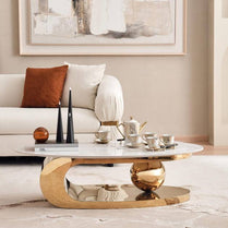 Modern living room with a gold coffee table, white sofa, and abstract art on the wall.