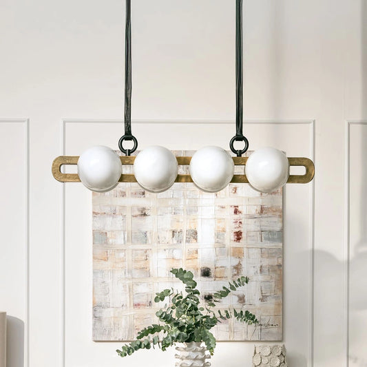 Modern pendant light fixture with white spherical bulbs hanging against a neutral wall.