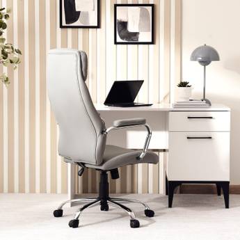 Modern office desk with a chair and laptop in a well-lit room.
