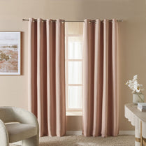 Pink curtains with grommets in a room with a chair and table.