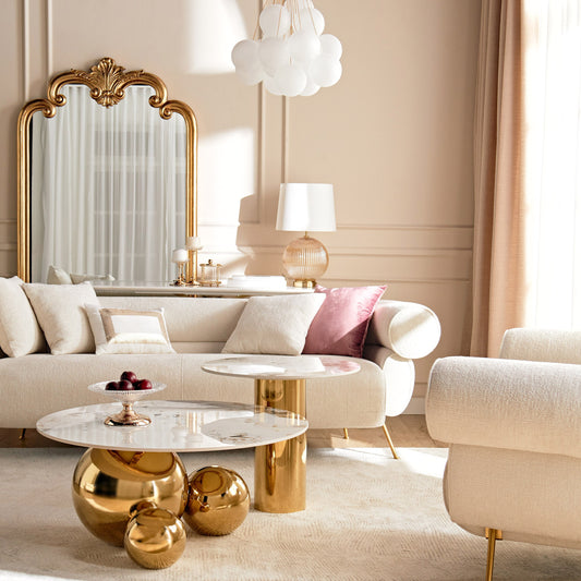 Luxurious living room with gold and marble coffee table, beige sofa, and decorative mirror.