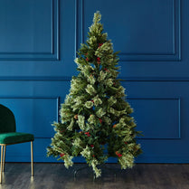 Decorative Christmas tree with green leaves and red berries against a blue paneled wall.