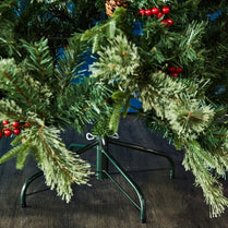 Artificial Christmas tree with green branches and red berries on a wooden floor.