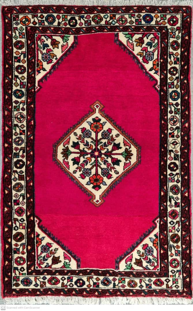 Decorative rug with a pink center and intricate border design.