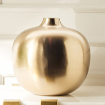 Gold vase on a light-colored surface with a neutral background