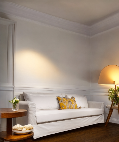 White sofa with a yellow pillow in a room with wooden floors and white walls. Milano Collection Sofa – Clean Lines, Lasting Comfort | Vella Concept