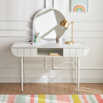 White vanity table with mirror and lamp in a room with a colorful rug.