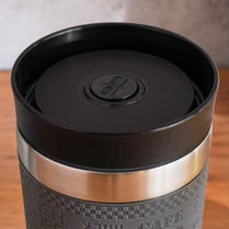 Black travel mug with a silver base on a wooden surface