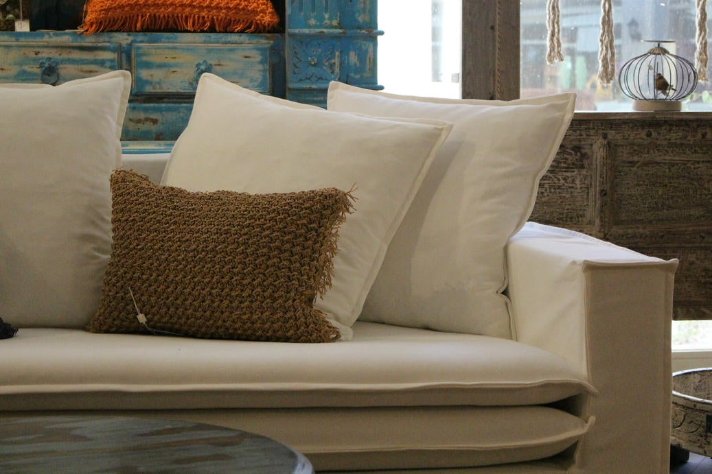 Beige sofa with white and brown cushions in a room setting. New York Collection Sofa – Live in the Now | Vella Concept