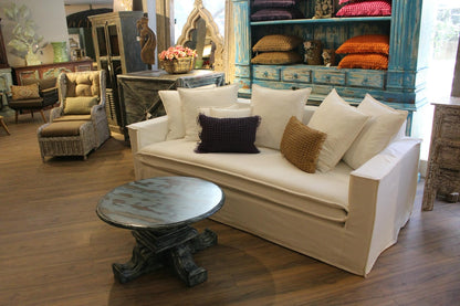 Living room with beige sofa, decorative pillows, and a round table. New York Collection Sofa – Live in the Now | Vella Concept